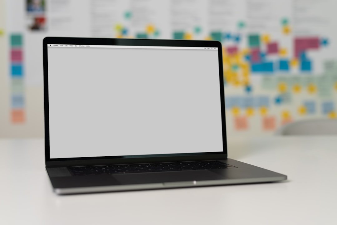a closed laptop on a desk with blurred colorful sticky notes in the background